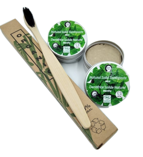 Bamboo toothbrush and natural solid toothpaste in green packaging on a white background