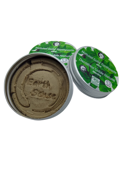 Open container of natural toothpaste with green lid on a white background