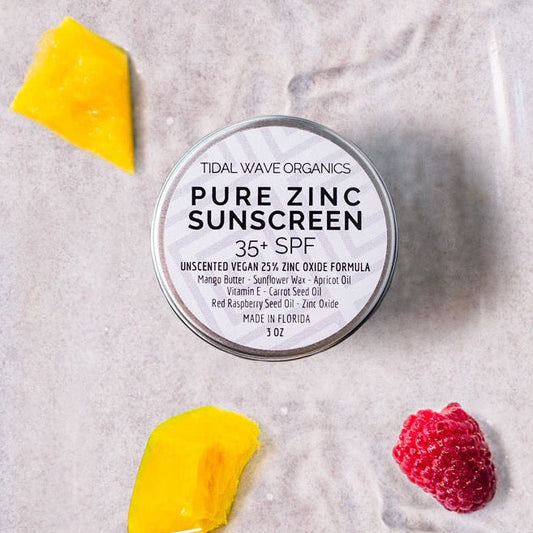 Tin of Tidal Wave Organics Pure Zinc Sunscreen with a piece of mango and raspberry on a light background