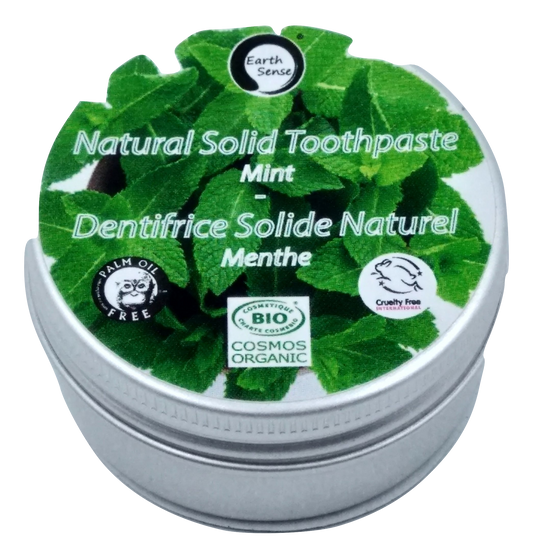 Natural solid toothpaste container with green leaf design and branding on a white background