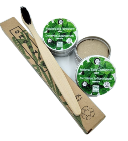 Bamboo toothbrush and natural solid toothpaste in green packaging on a white background