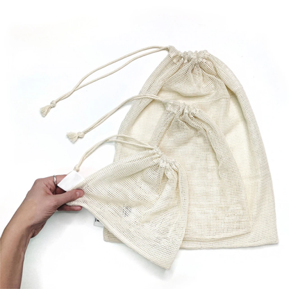Beige drawstring bag held by a hand on a white background