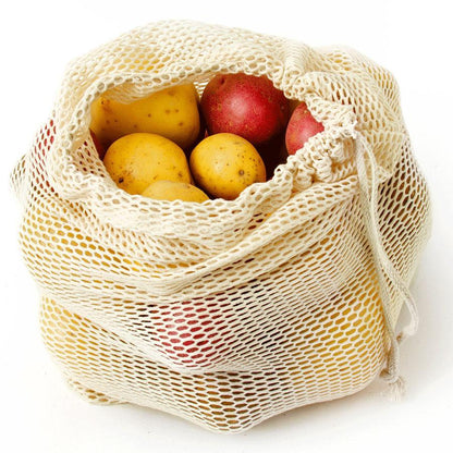 Beige mesh bag filled with potatoes on a white background